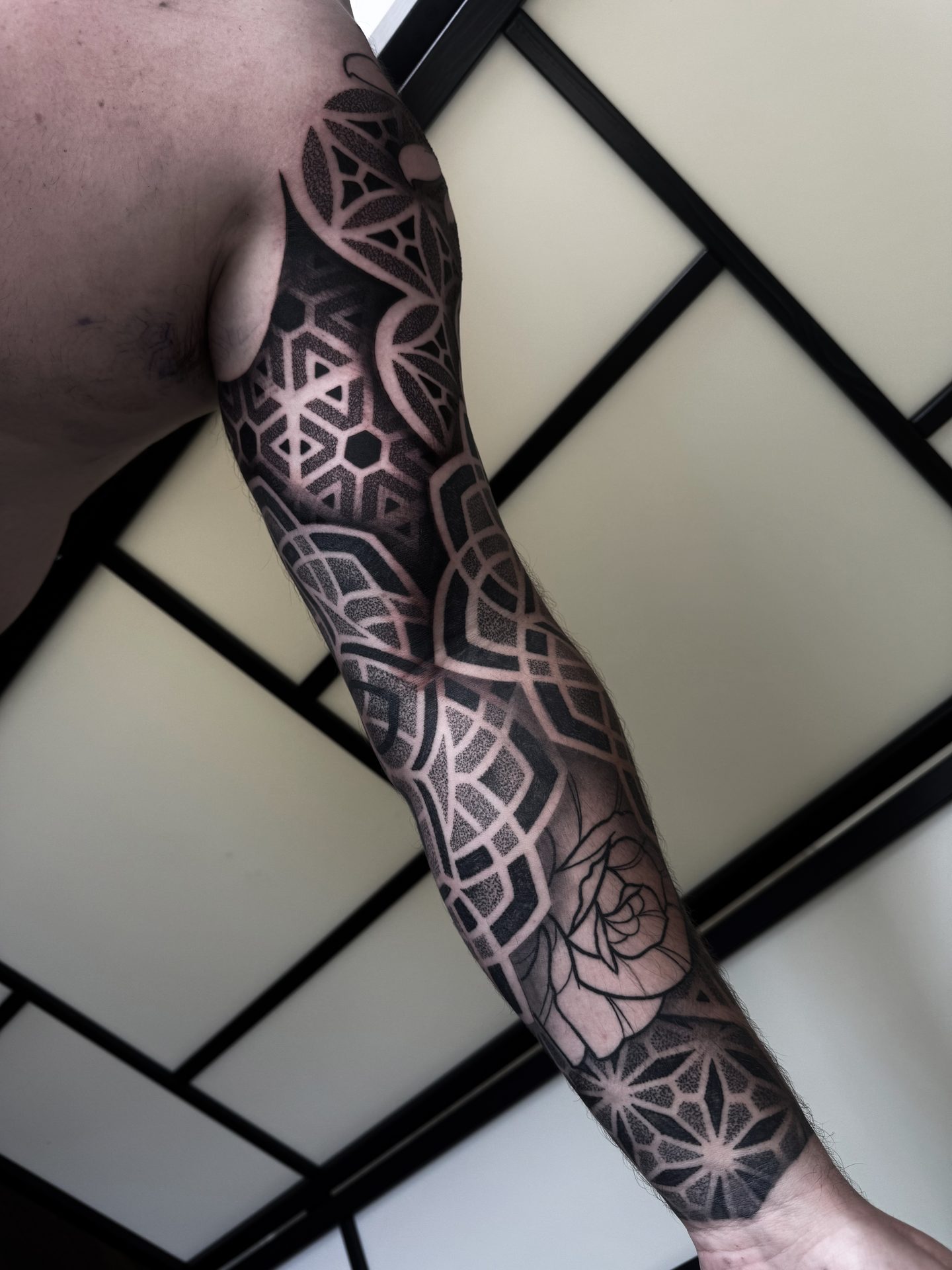 Geometric blackwork arm sleeve tattoo by Liam Couper