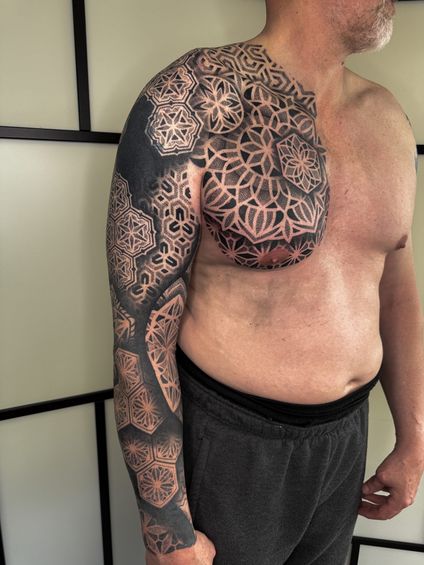 Geometric chest panel and sleeve tattoo by Liam Couper
