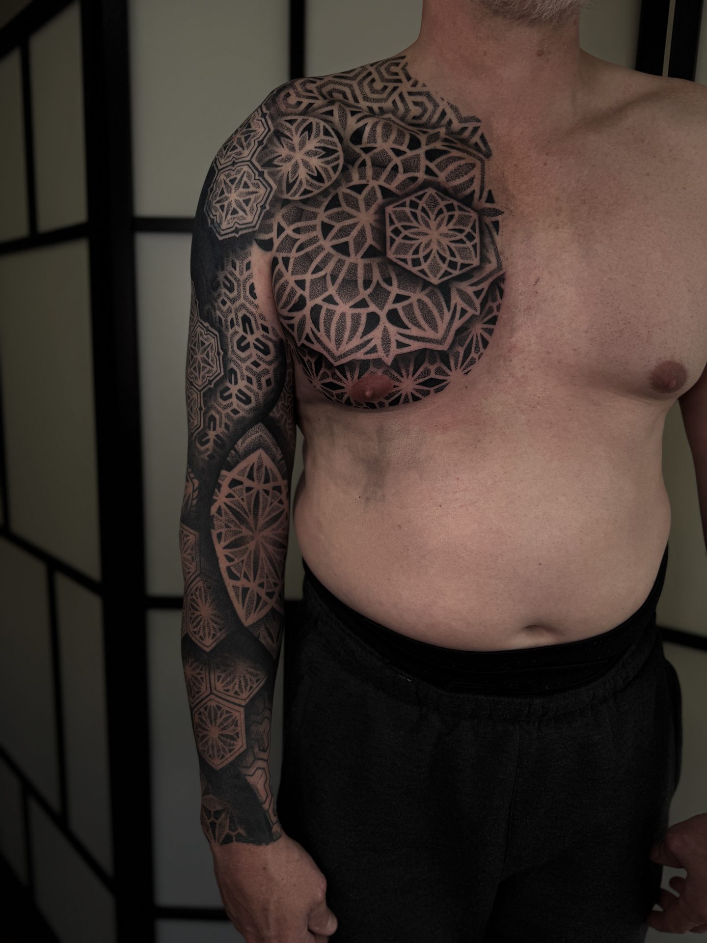 Geometric chest piece and full sleeve tattoo by Liam Couper