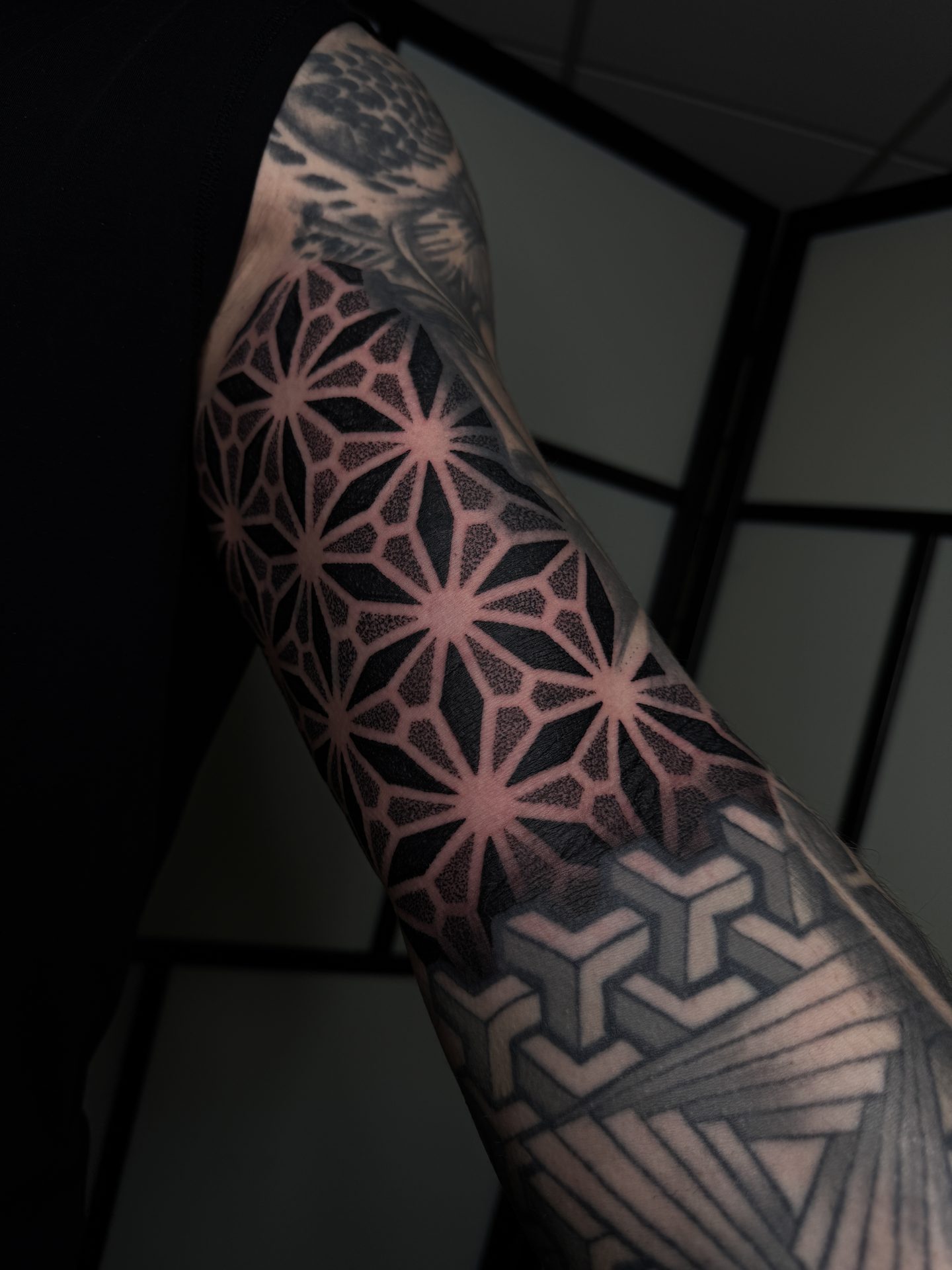 Dark geometric forearm sleeve tattoo by Liam Couper