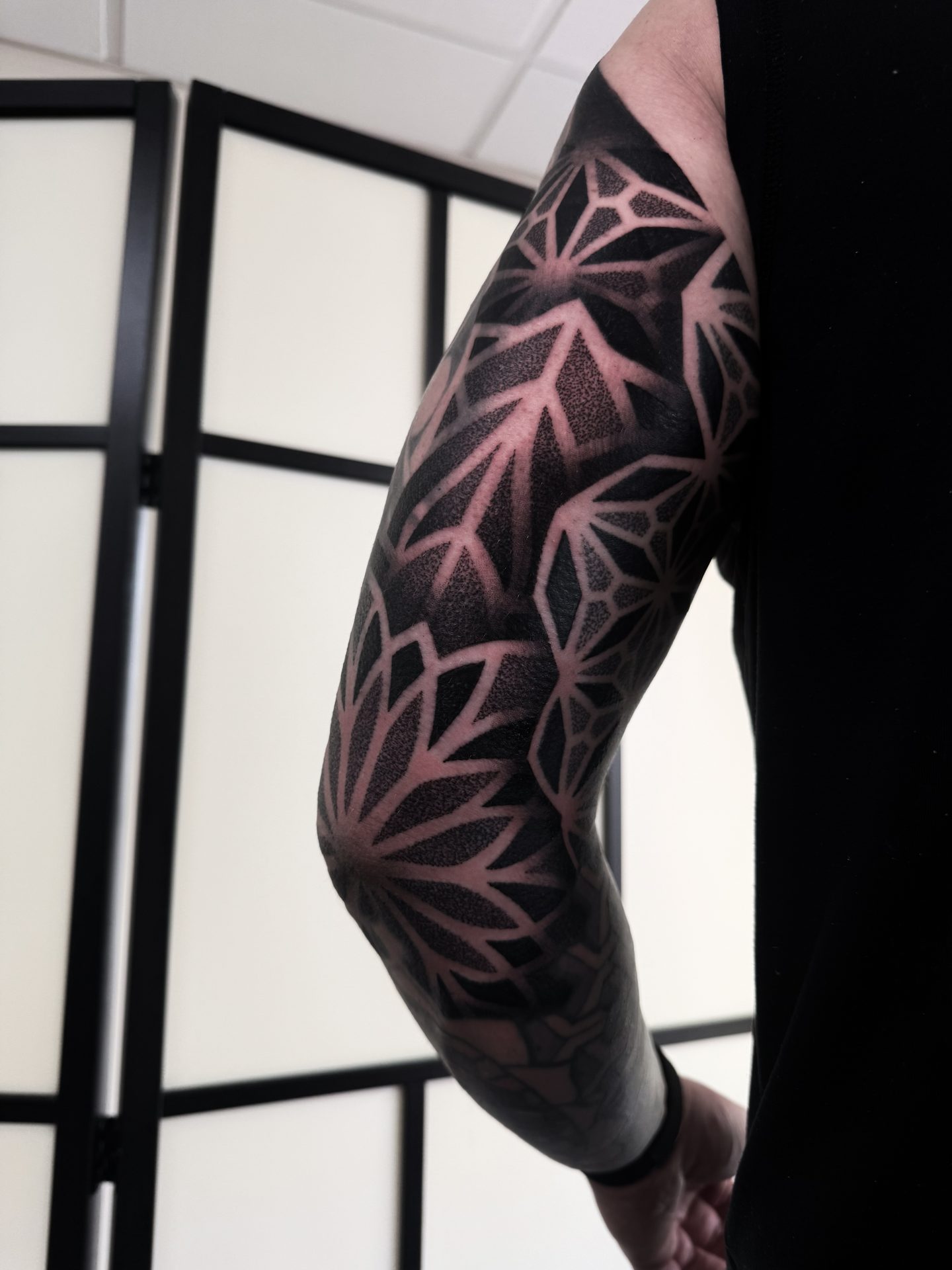 Dark geometric blackwork full sleeve tattoo by Liam Couper