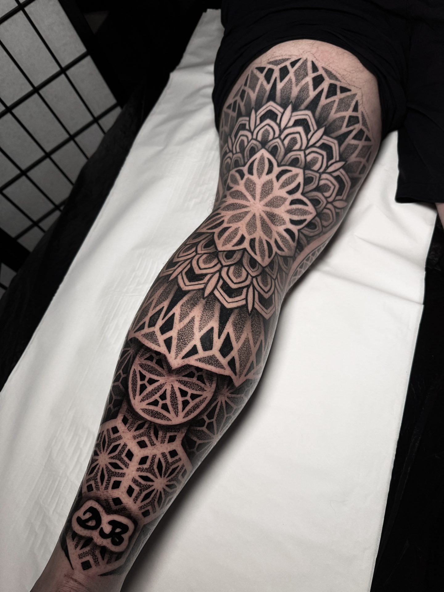 Front view of a geometric mandala leg sleeve tattoo by Liam Couper
