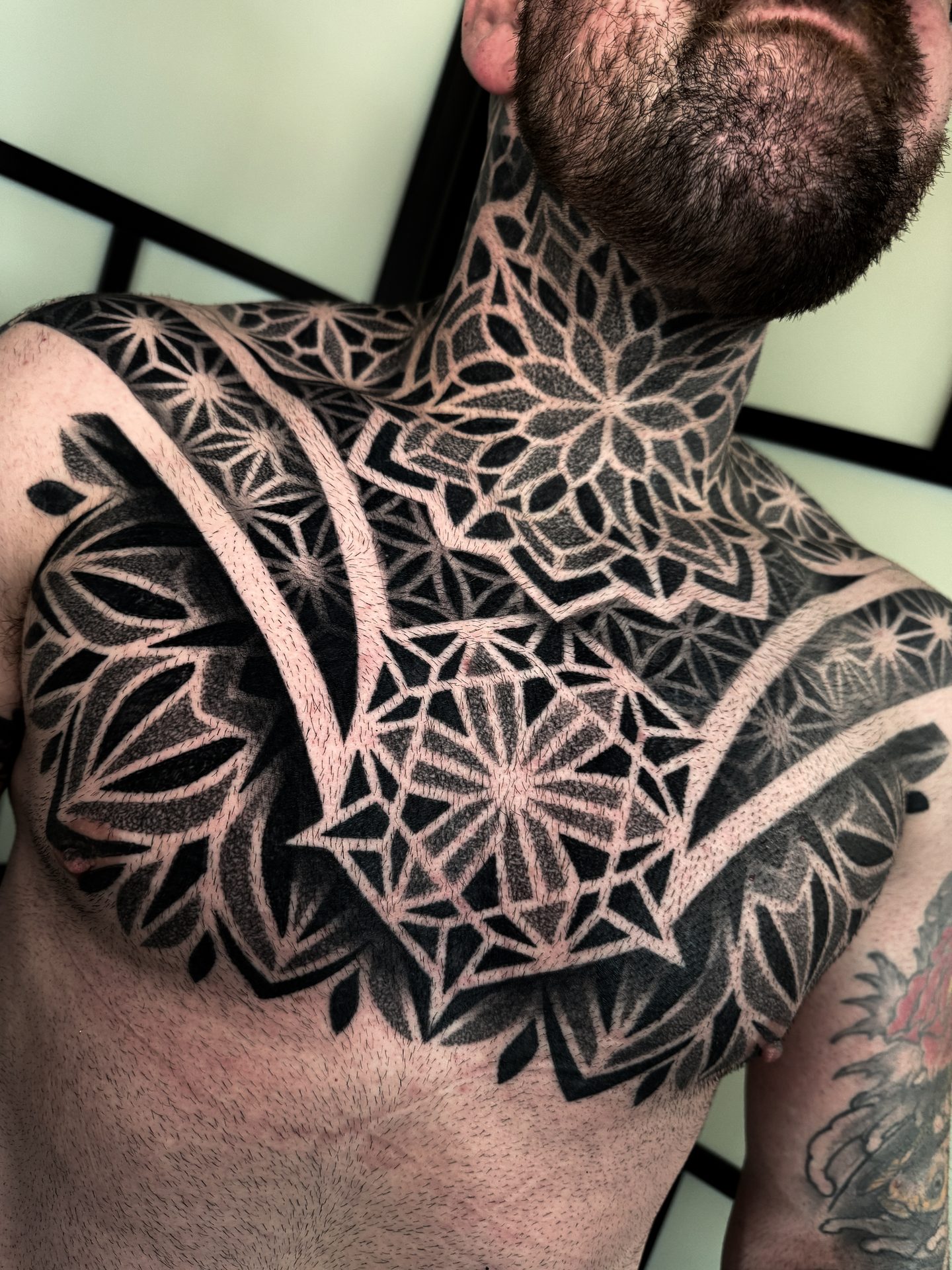 Geometric neck and chest blackwork tattoo by Liam Couper