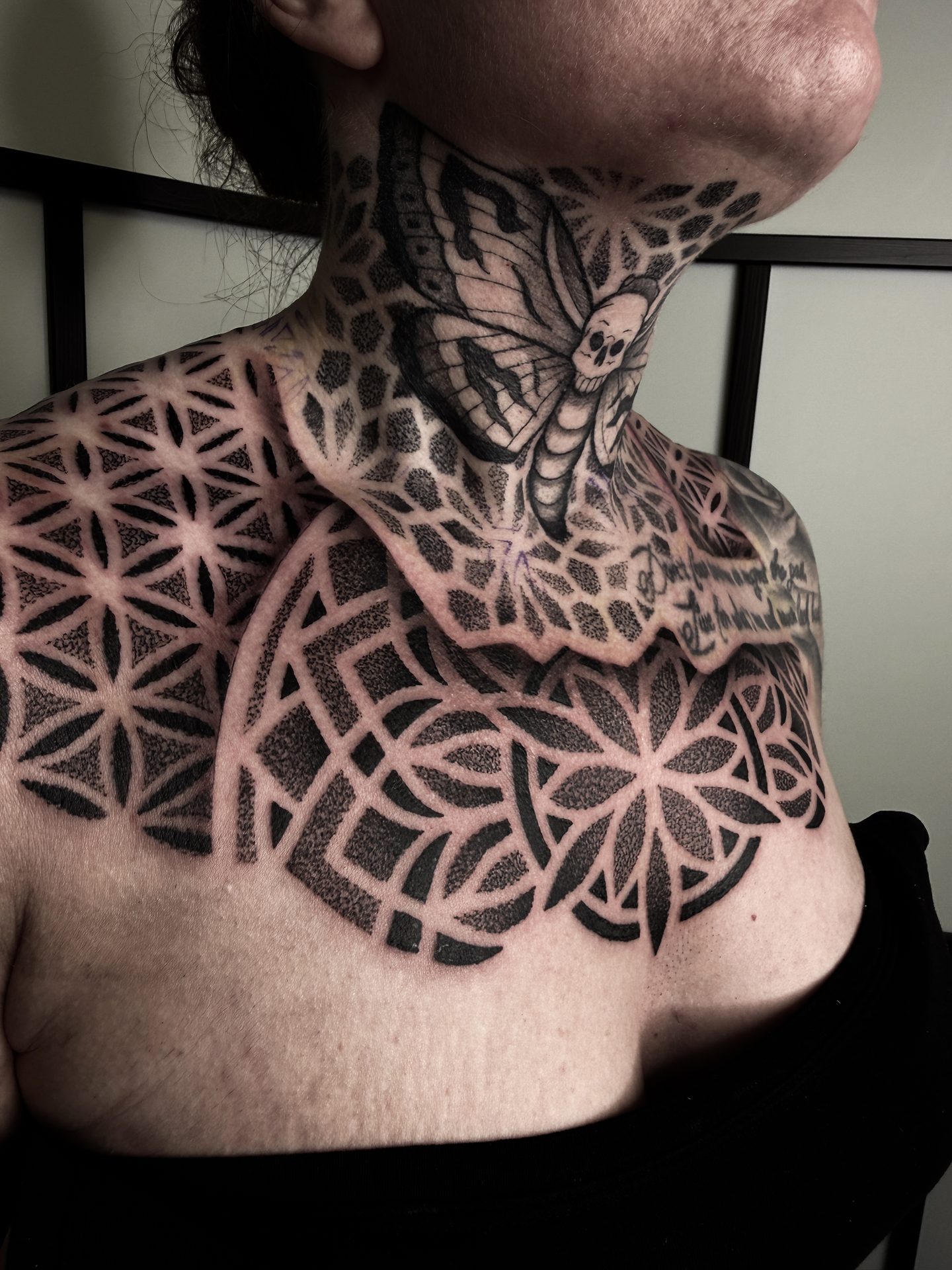 Geometric blackwork neck and chest tattoo by Liam Couper