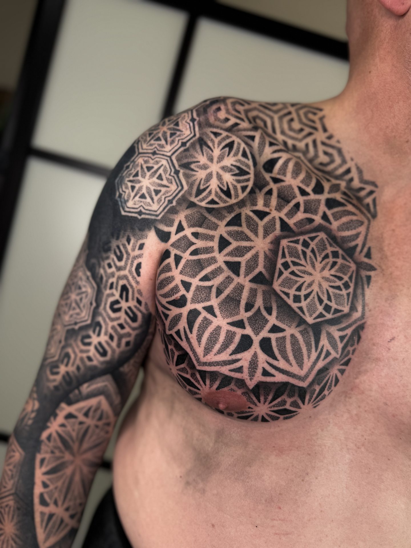 Large geometric mandala shoulder and chest tattoo by Liam Couper