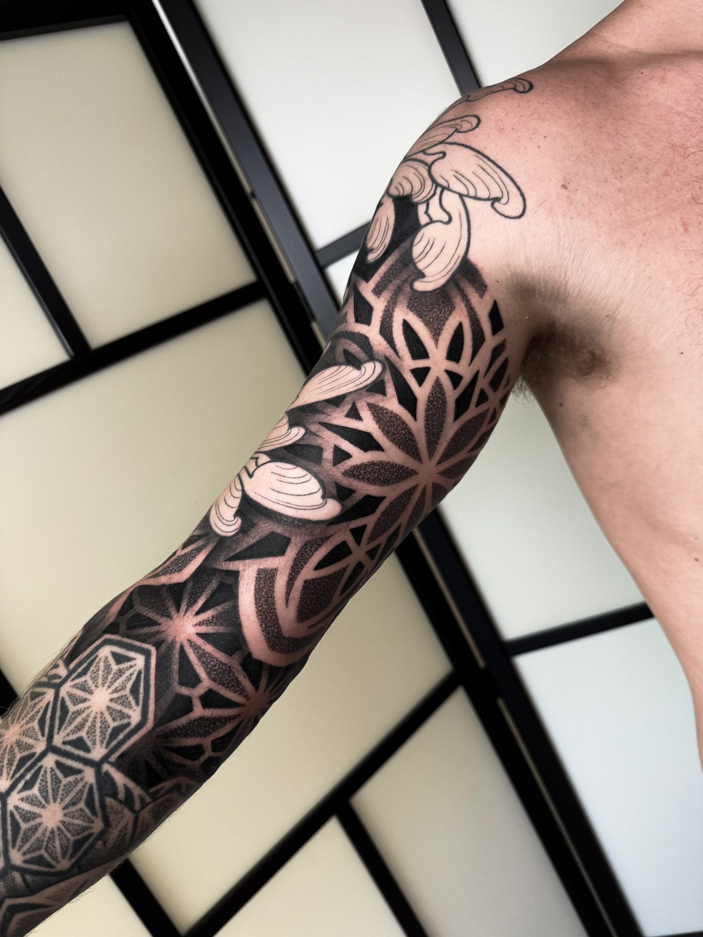 Geometric sleeve tattoo across arm and hand by Liam Couper