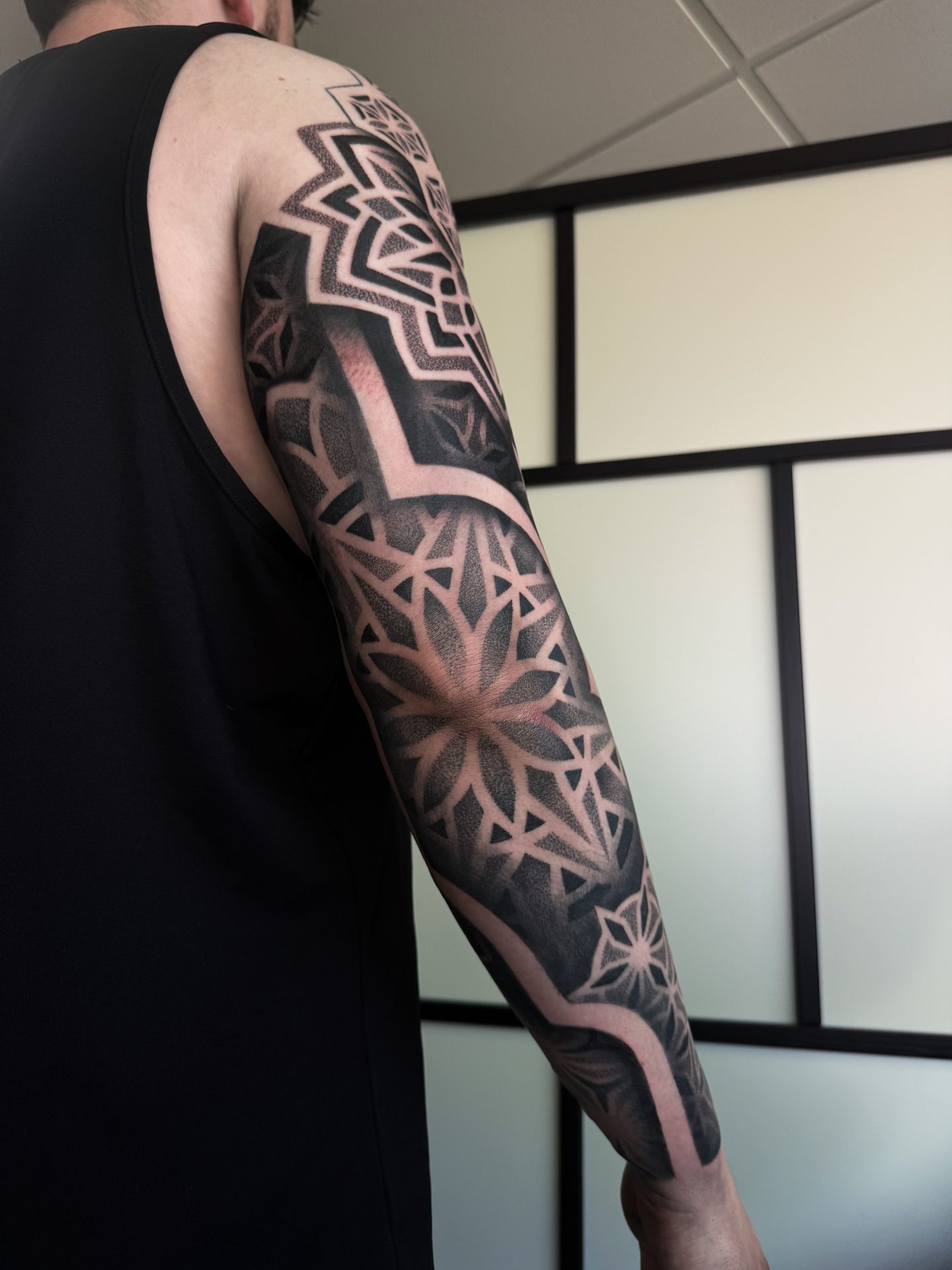 Profile view of a geometric blackwork sleeve tattoo by Liam Couper