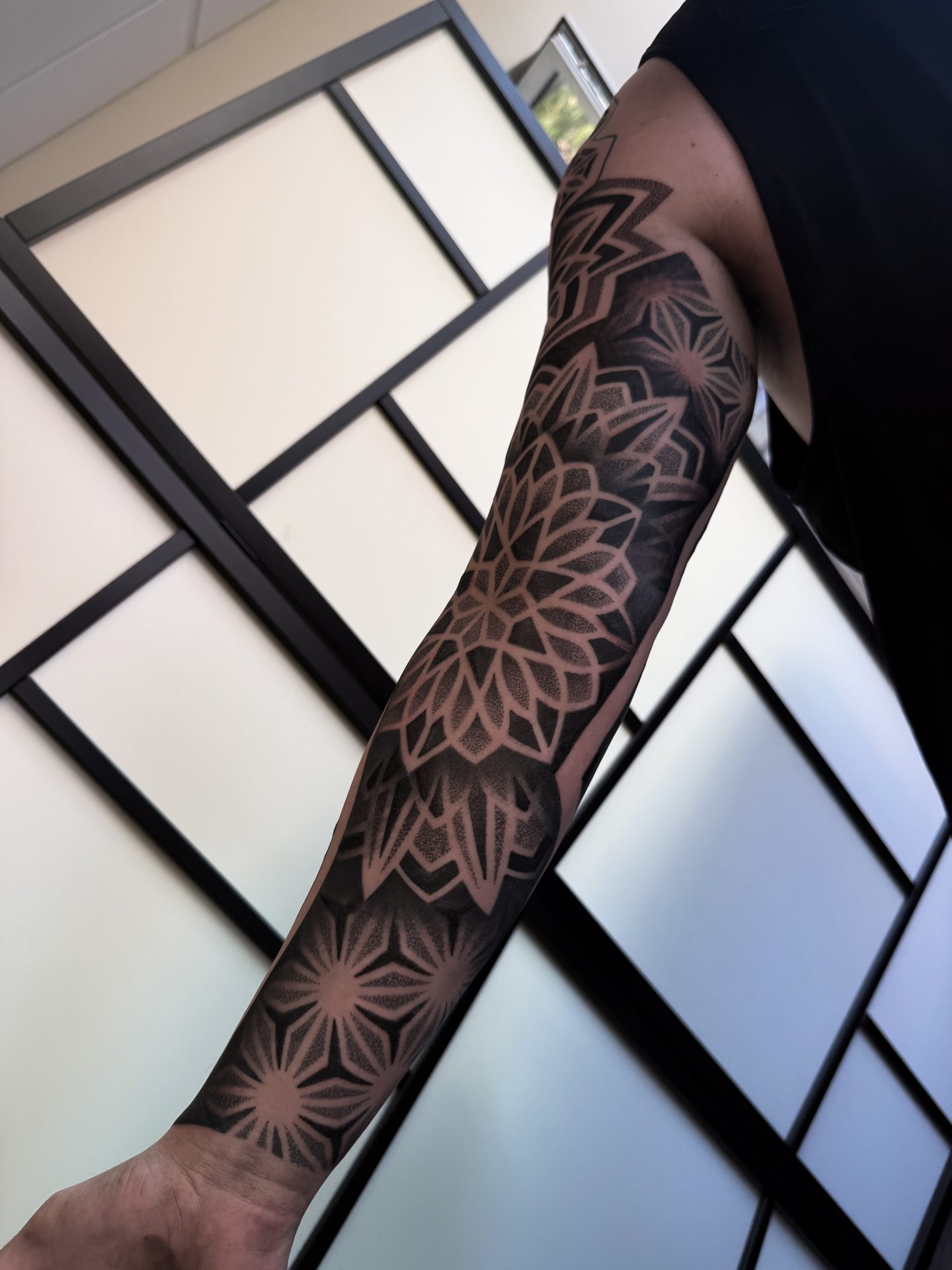 Geometric mandala sleeve tattoo with raised arm by Liam Couper