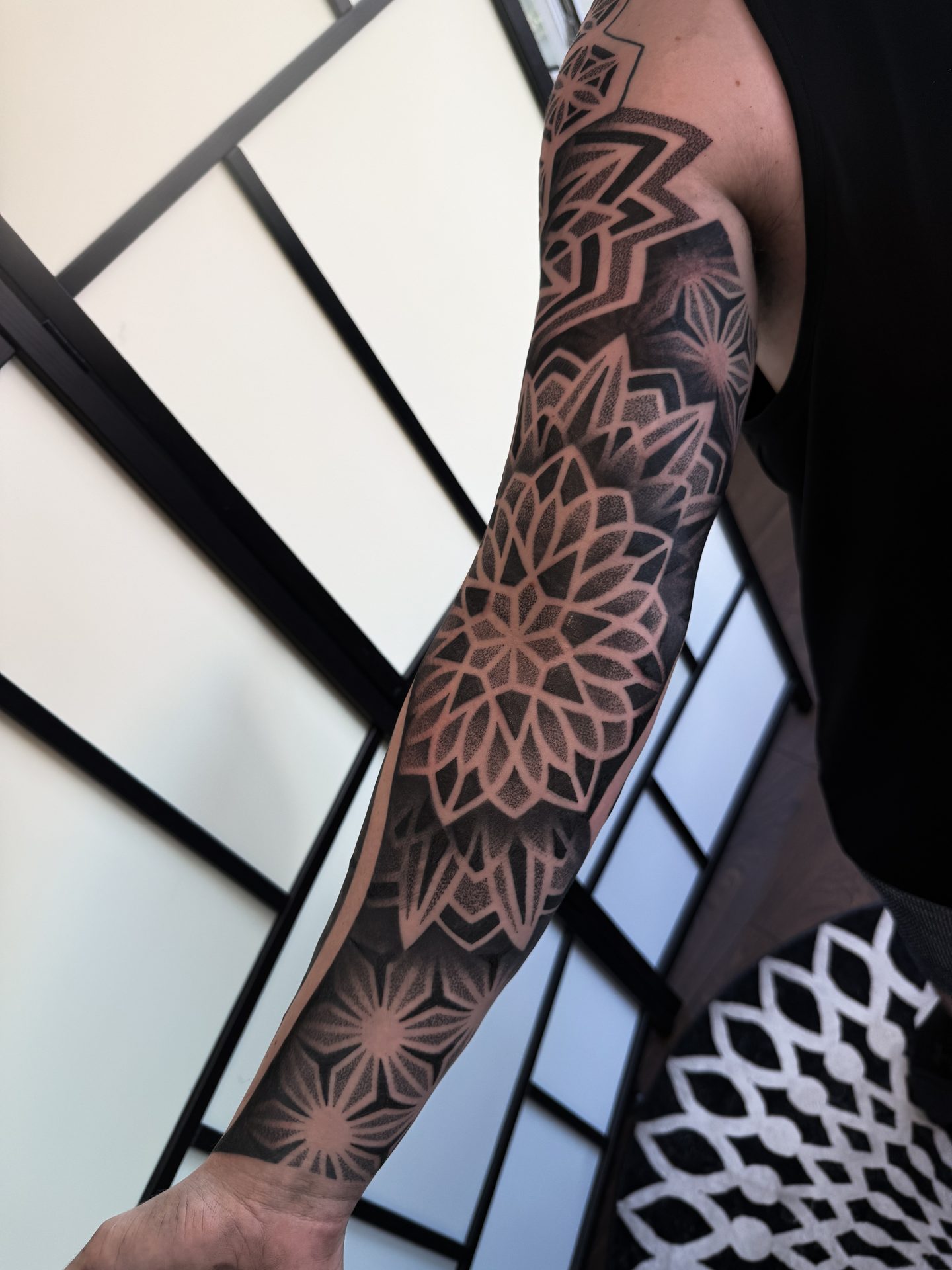 Geometric dotwork sleeve tattoo in front of the studio screen
