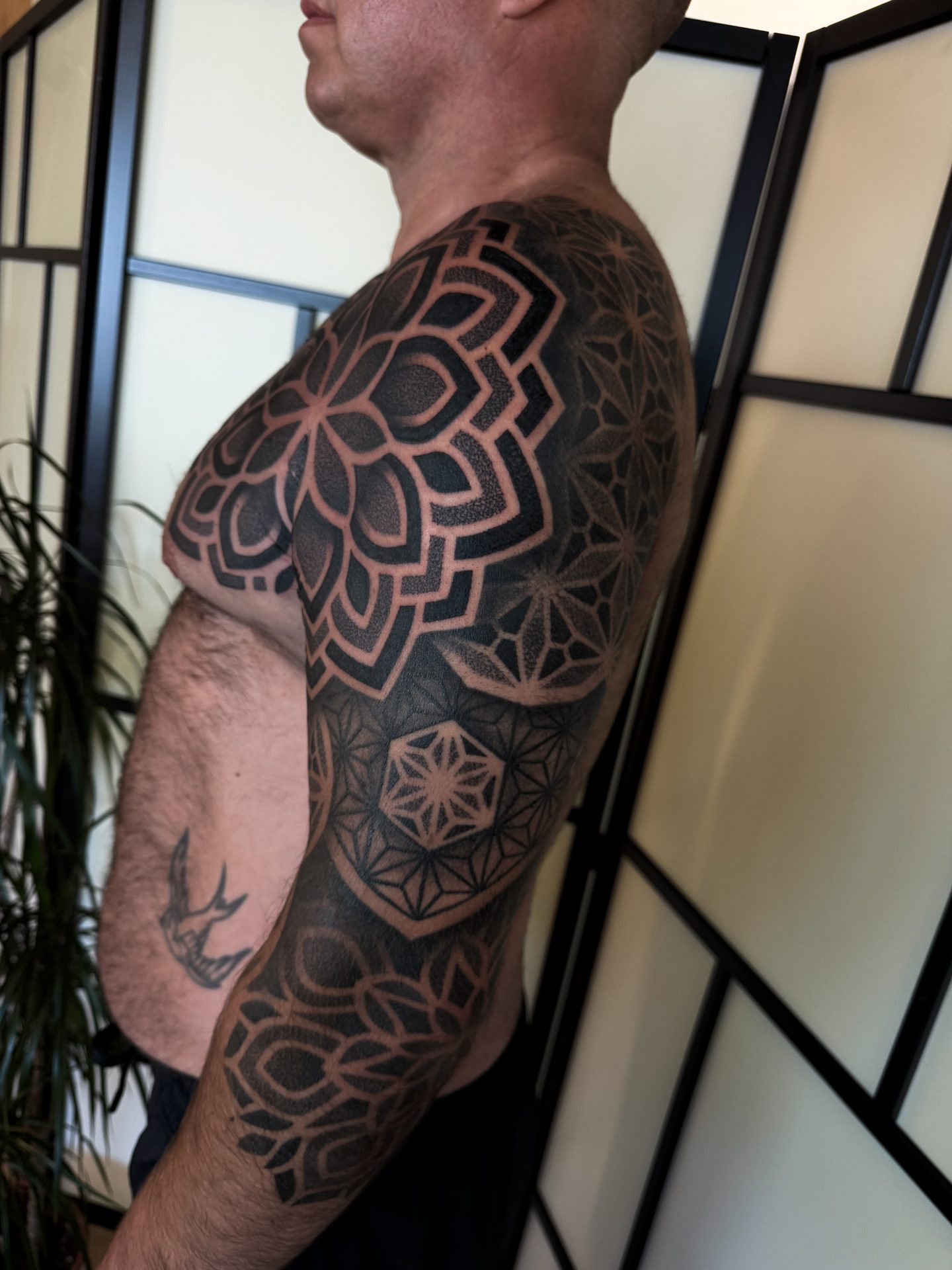 Geometric torso and mask style chest tattoo, side view, by Liam Couper