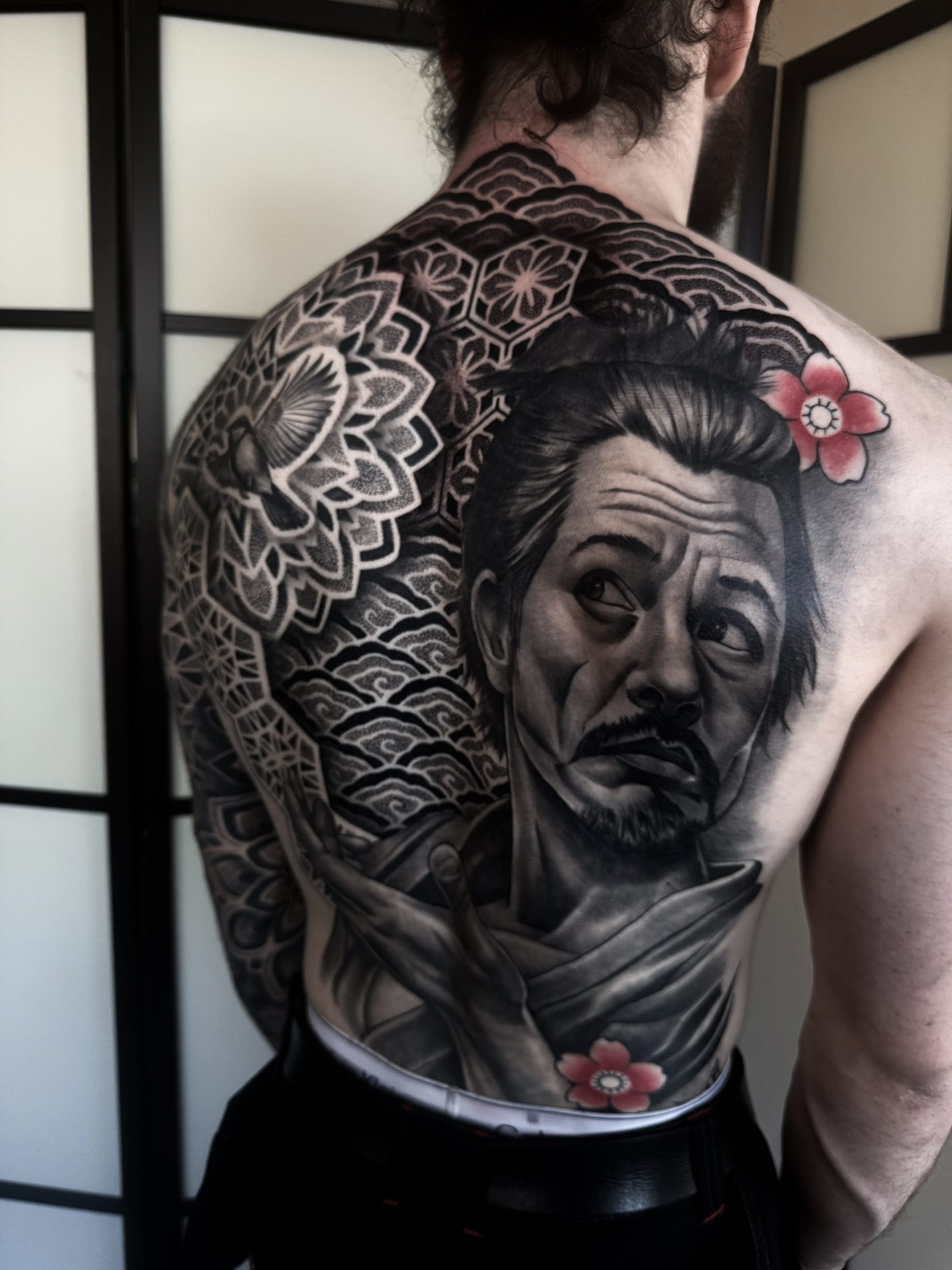 Back piece with realistic portrait and geometric patternwork by Liam Couper